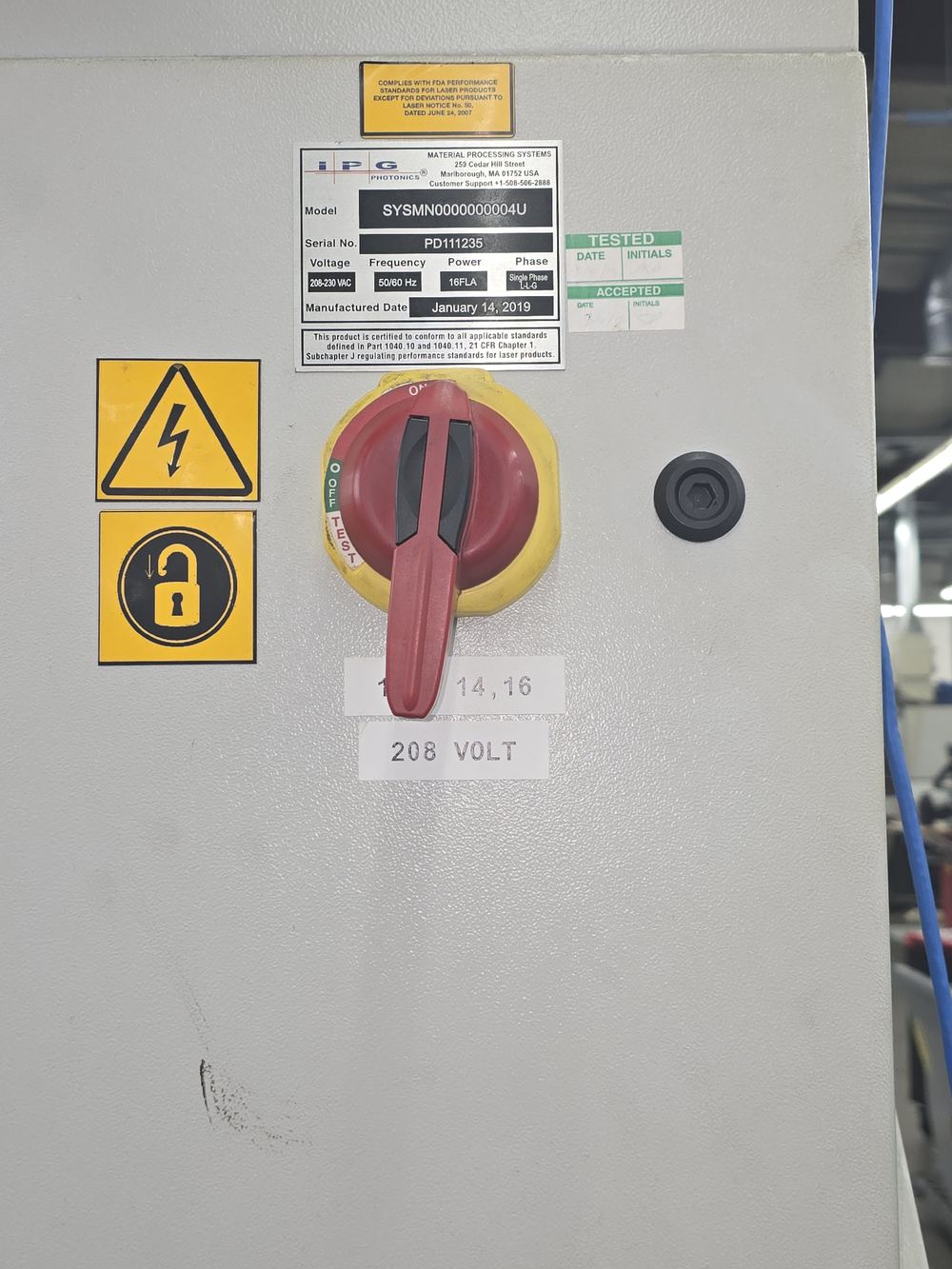 Rotary disconnect on the rear cabinet of the laser, red handle on a yellow plate, in the off position.