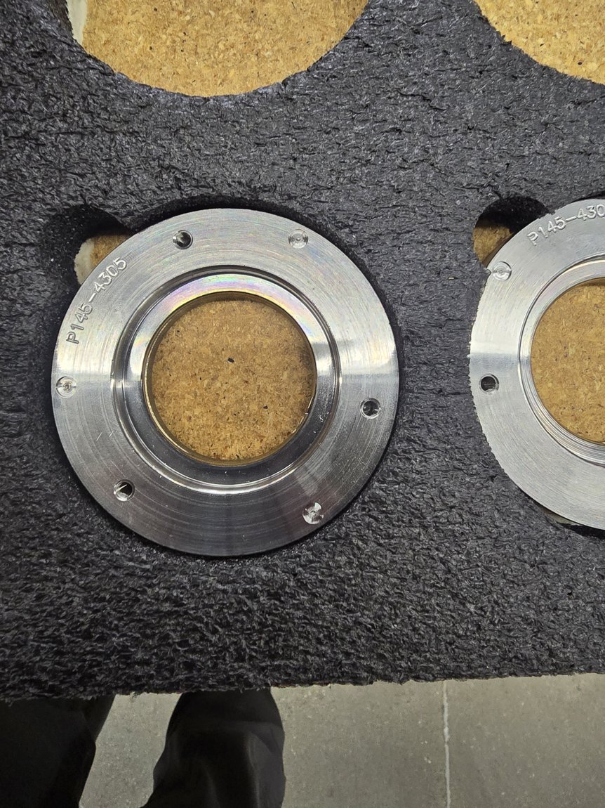 Two machined mag plates seated in cut-outs of a black foam tray, each engraved P145-4305.