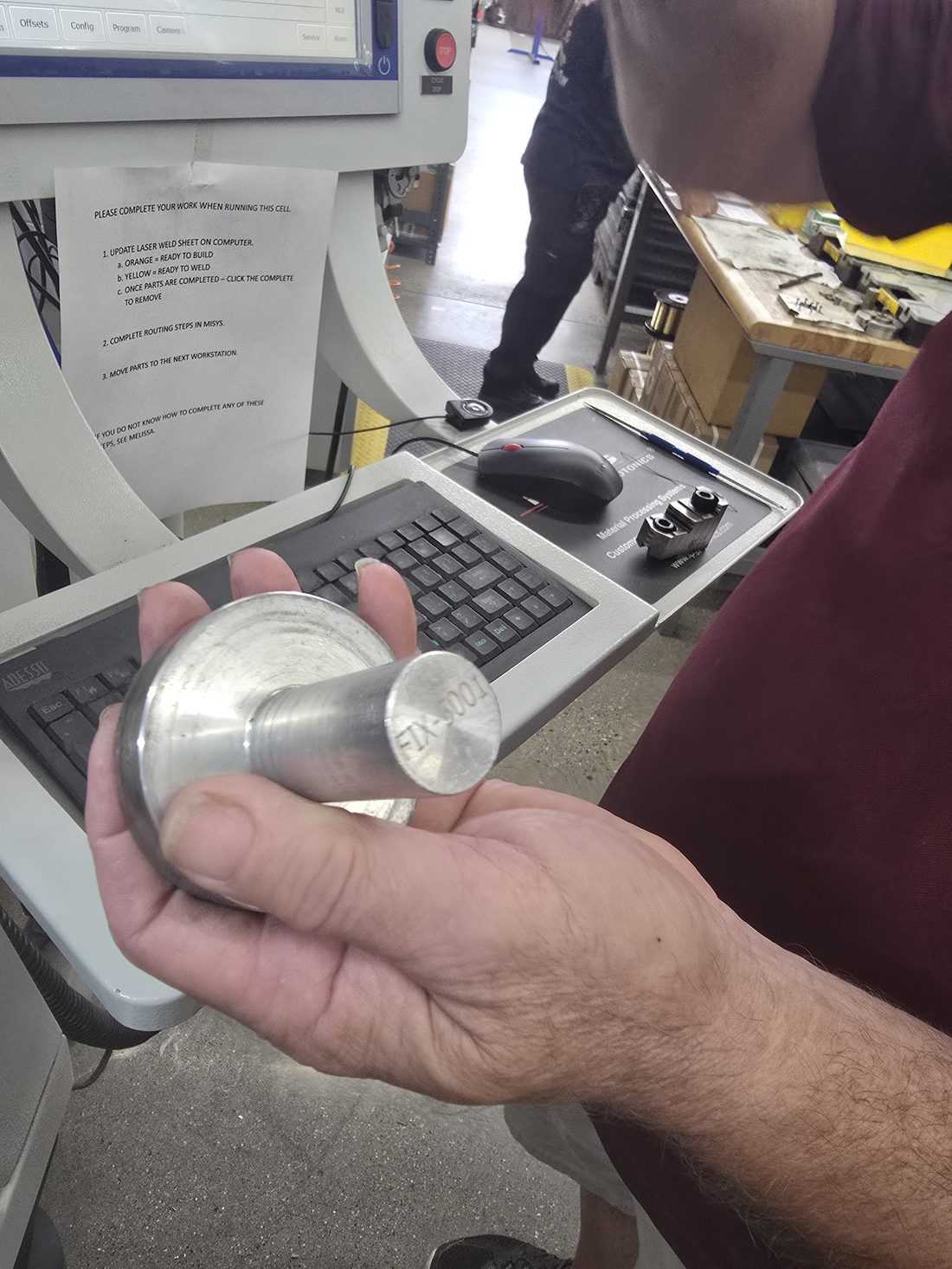 Mike holding the aluminium fixture with FIX-5001 hand-stamped into the flat end face of the shank.